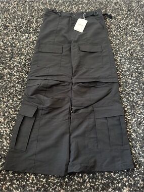 Black techwear-style convertible cargo pants with detachable zip-off lower legs.
